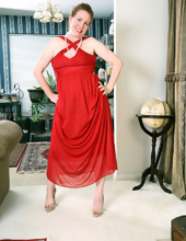Playful mature redhead takes off the dress leaving just white necklaces